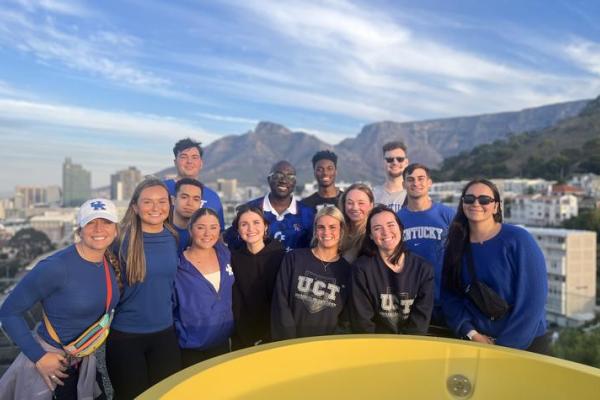 Students in South Africa with mountains behind them smiling at camera