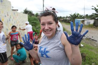 Student doing community project with blue paint on hands