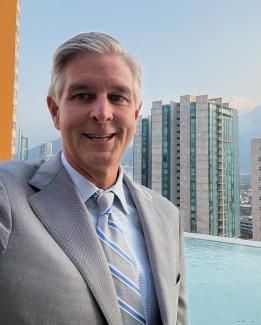 Michael Bowling looks to camera in gray suit with city in background