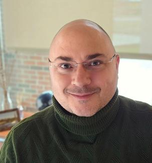 Man in sweater looks to camera