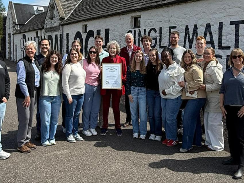 Group poses in front of distillery in Scotland